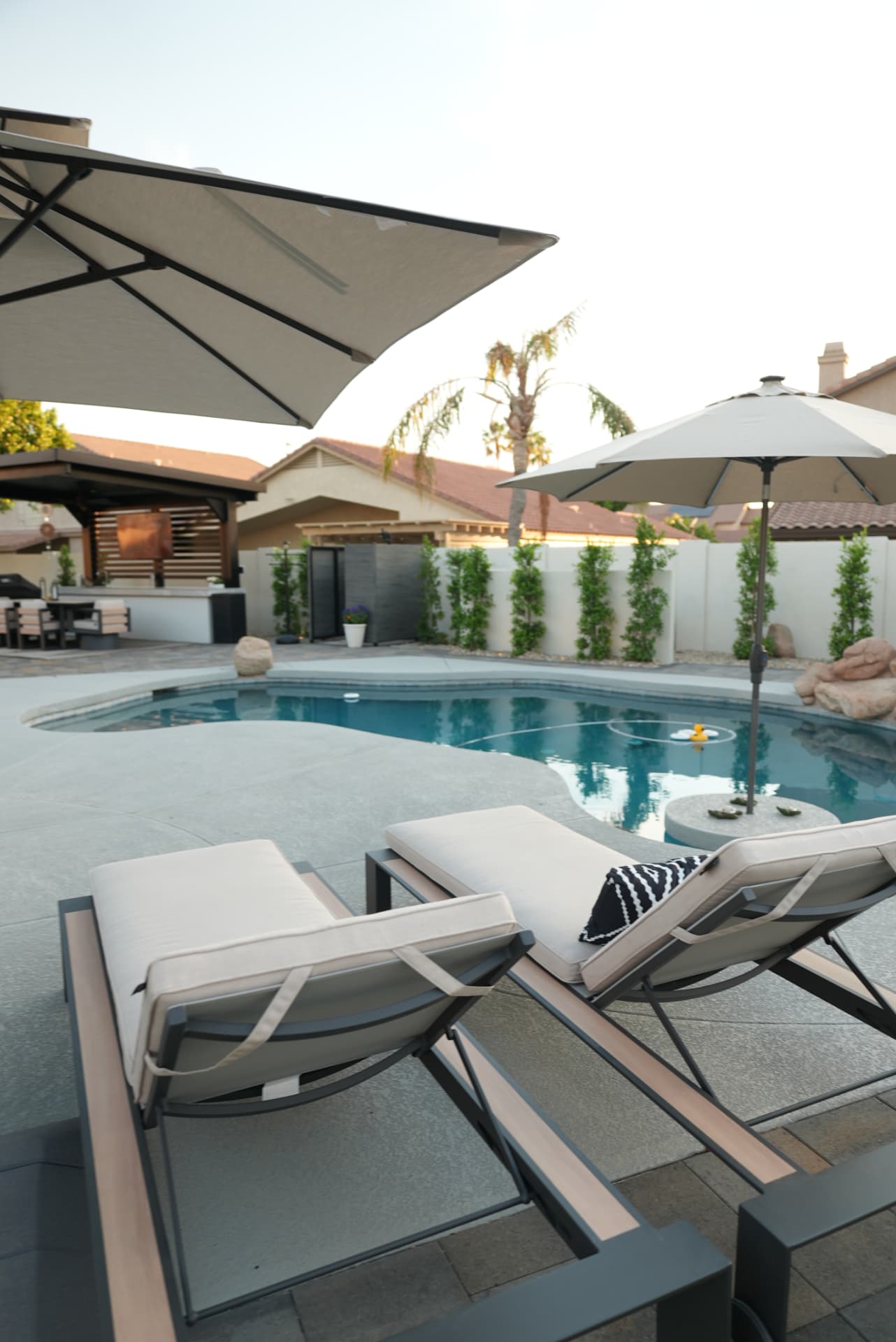 Poolside loungers under a large cantilever umbrella beside a pool