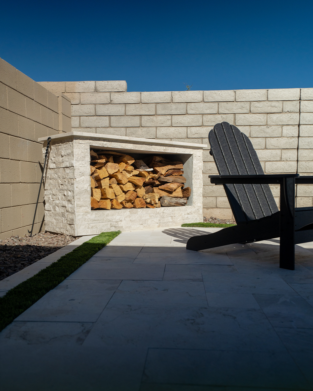 Stone-clad firewood storage niche beside a black Adirondack chair