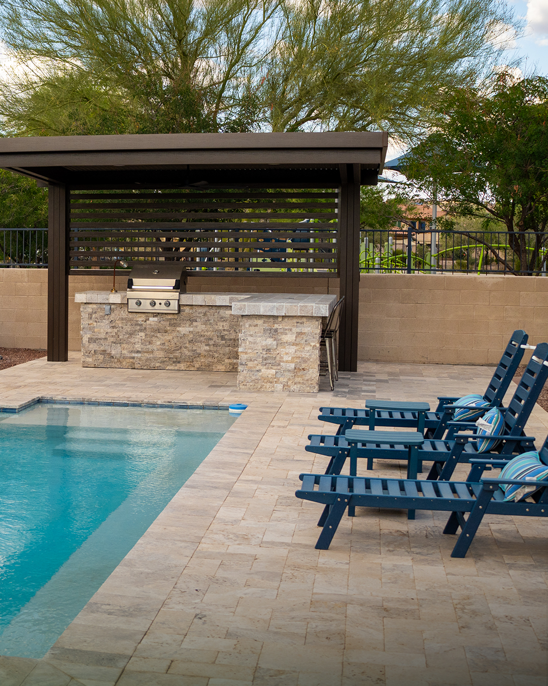 Stacked stone outdoor kitchen with grill and bar seating under a pavilion