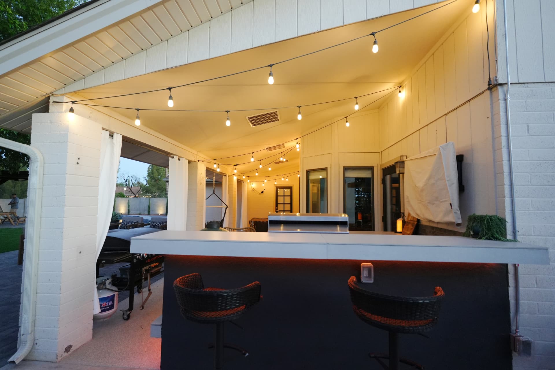 Covered patio with outdoor griddle, bar counter and string lights overhead
